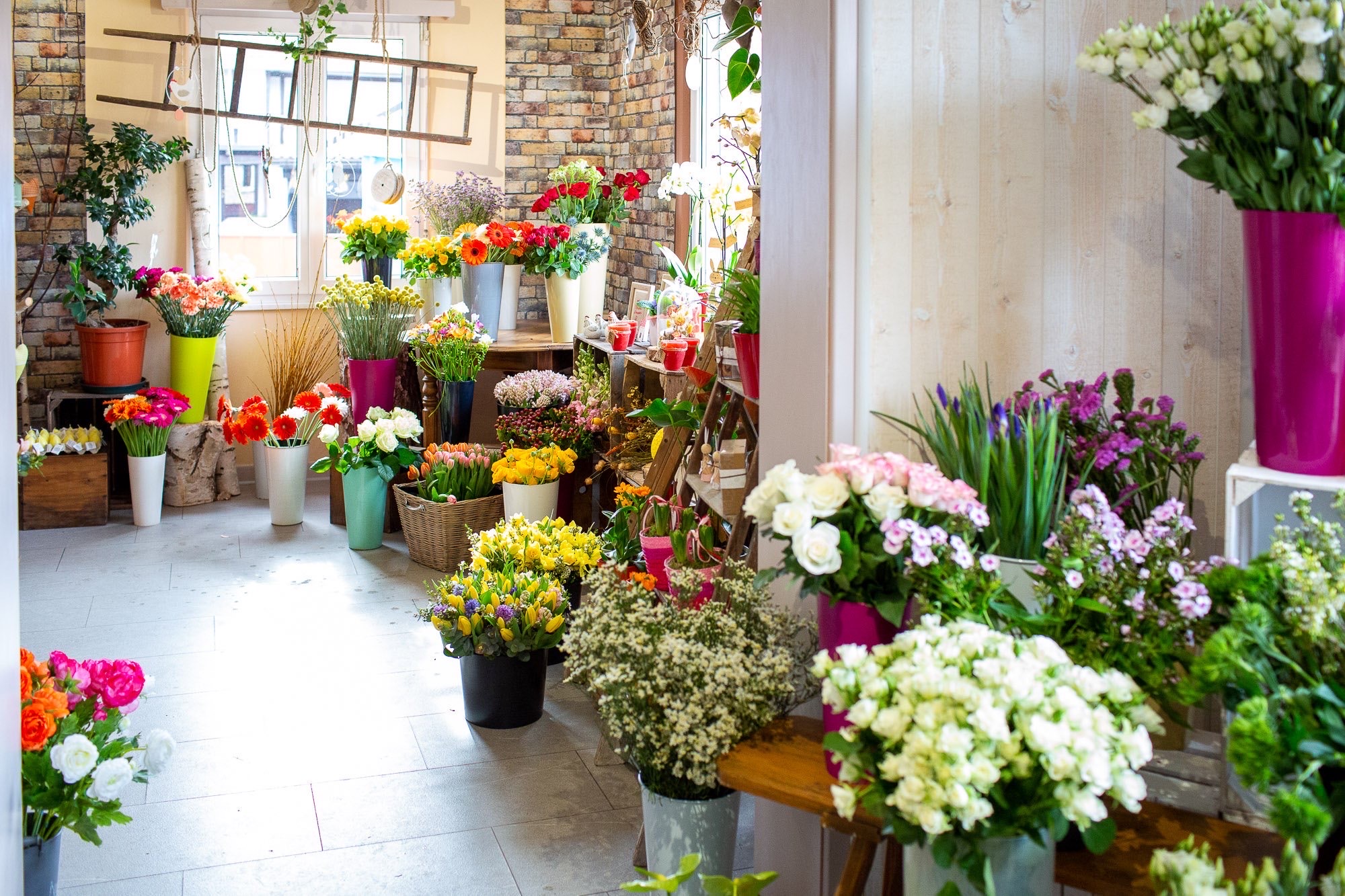 L’intérieur lumineux de La Vie en Rose : fleurs colorées, bois et brique.